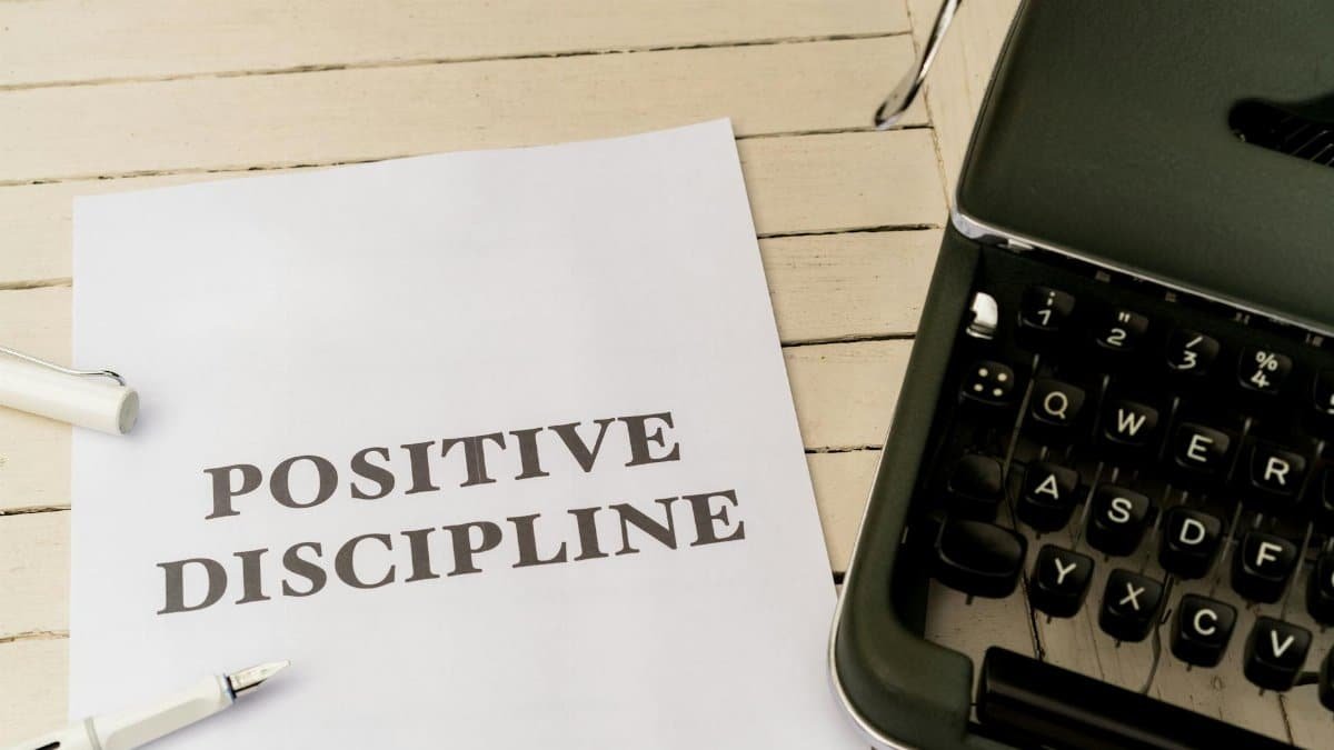 Vintage typewriter next to a paper with 'Positive Discipline' text, symbolizing communication and education.