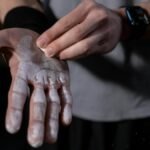 A detailed view of a hand applying gym chalk indoors, symbolizing fitness and preparation.