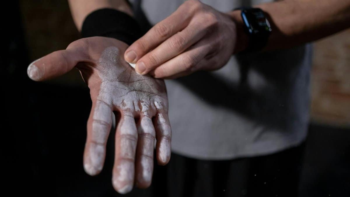 A detailed view of a hand applying gym chalk indoors, symbolizing fitness and preparation.
