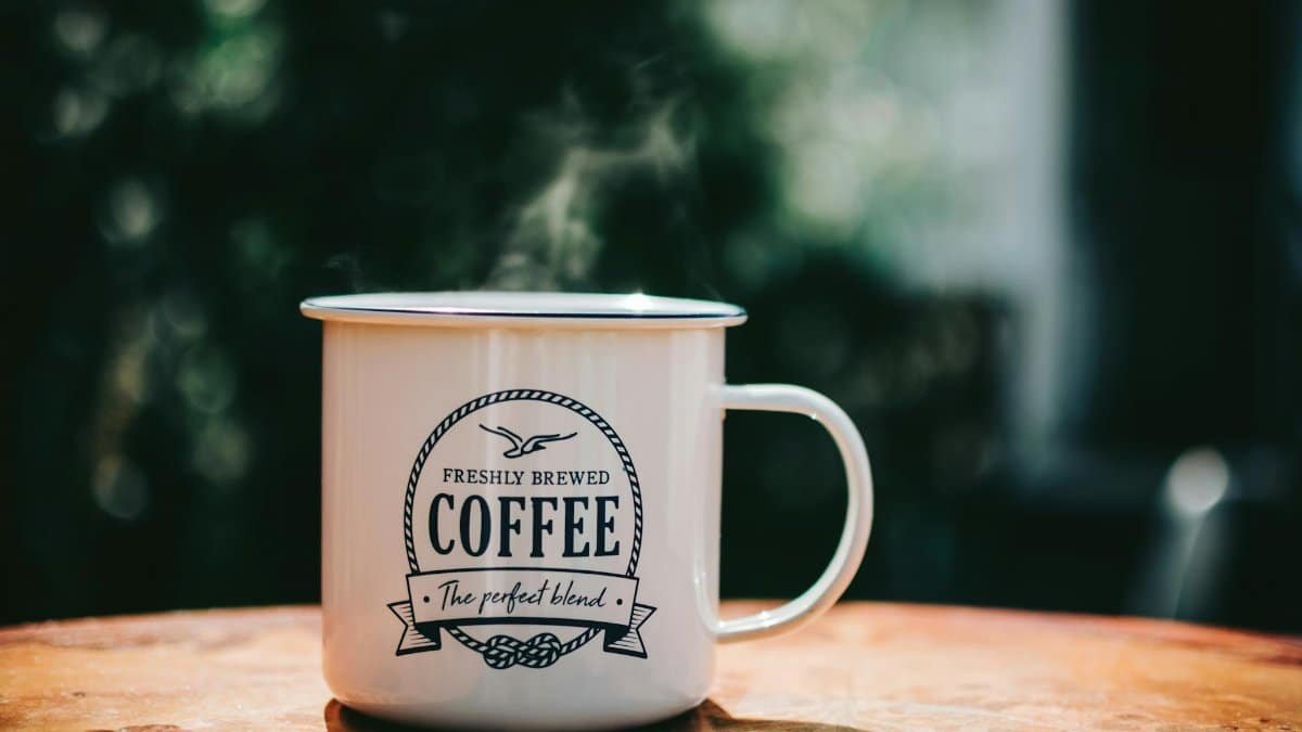 Warm coffee mug steaming on a rustic table, evoking cozy morning vibes.