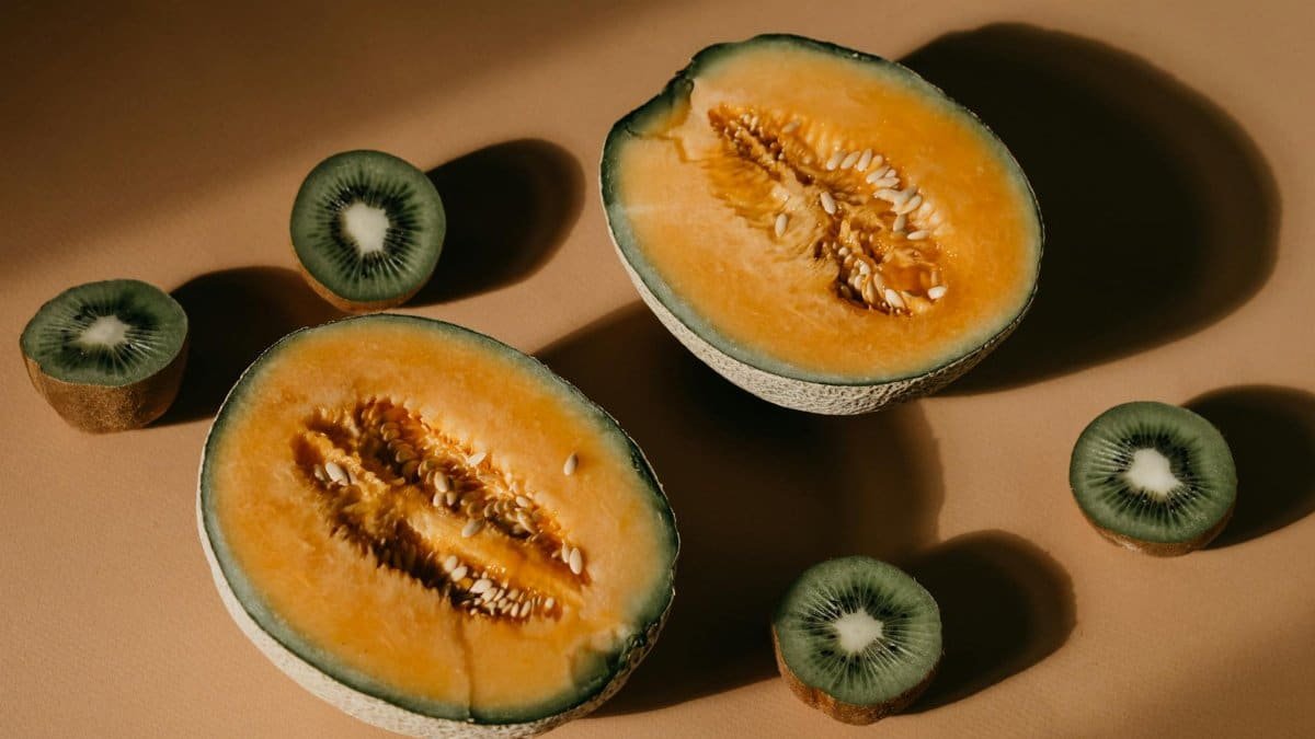 Aesthetic composition of cantaloupe and kiwi slices in warm lighting, showcasing fresh and juicy tropical fruits.