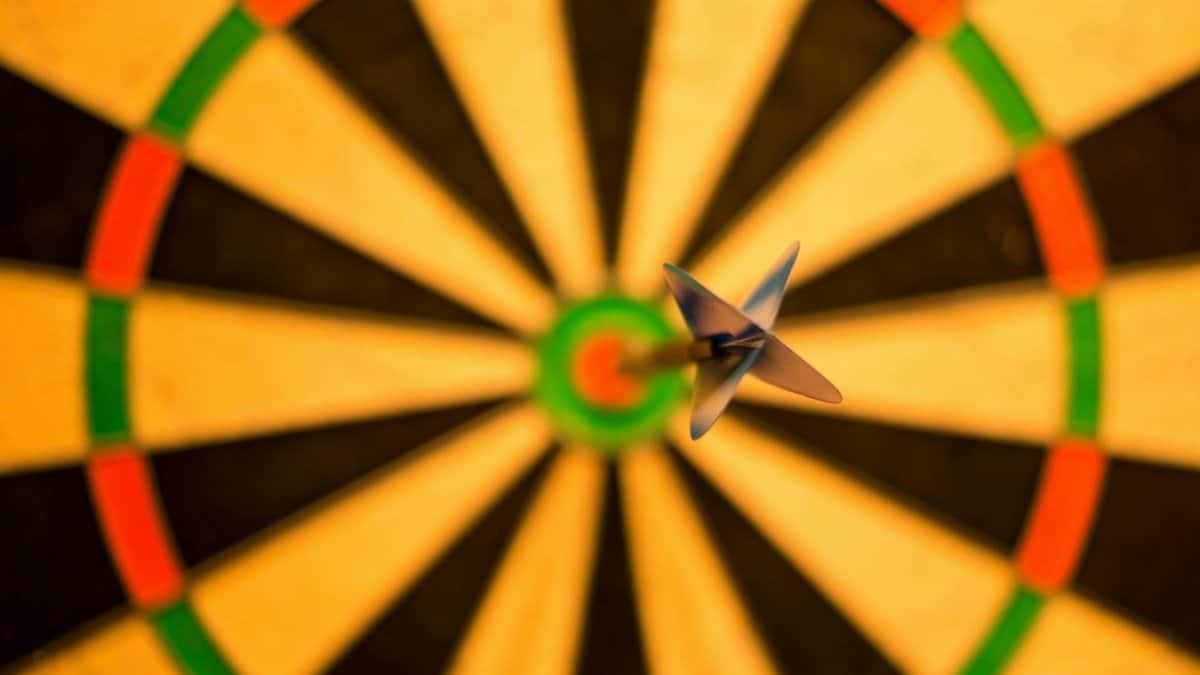 A close-up of a dart perfectly hitting the bullseye on a dartboard, symbolizing accuracy.