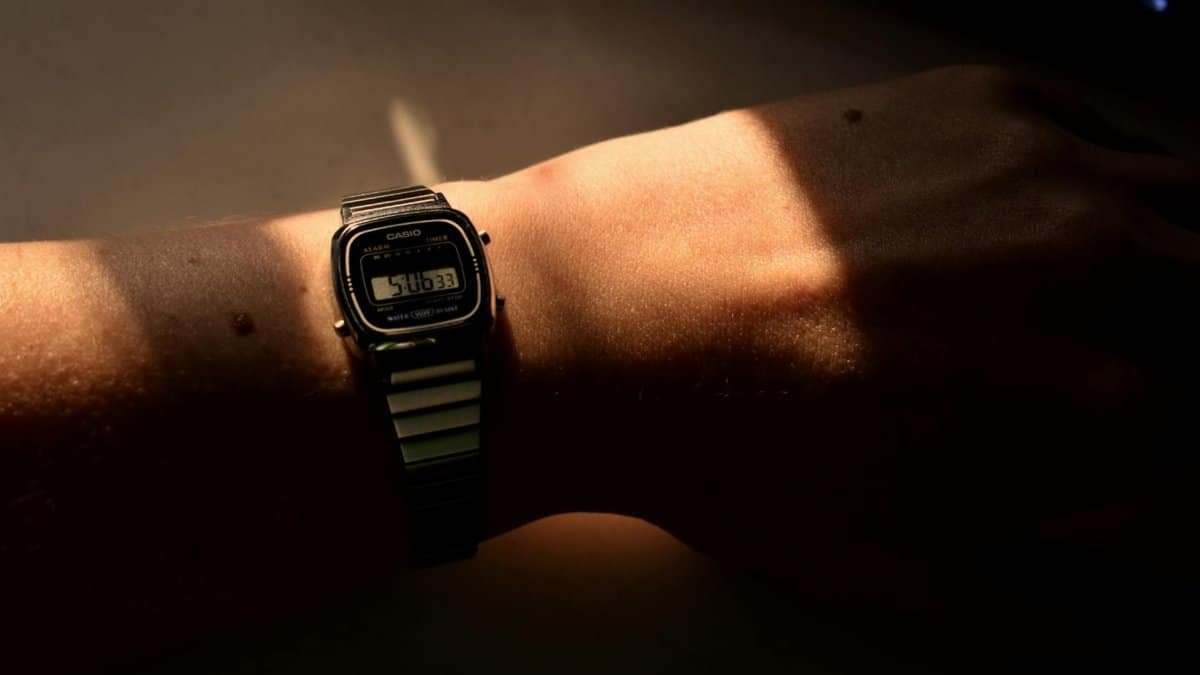 A close-up of a Casio wristwatch on a person's wrist, illuminated by warm light.