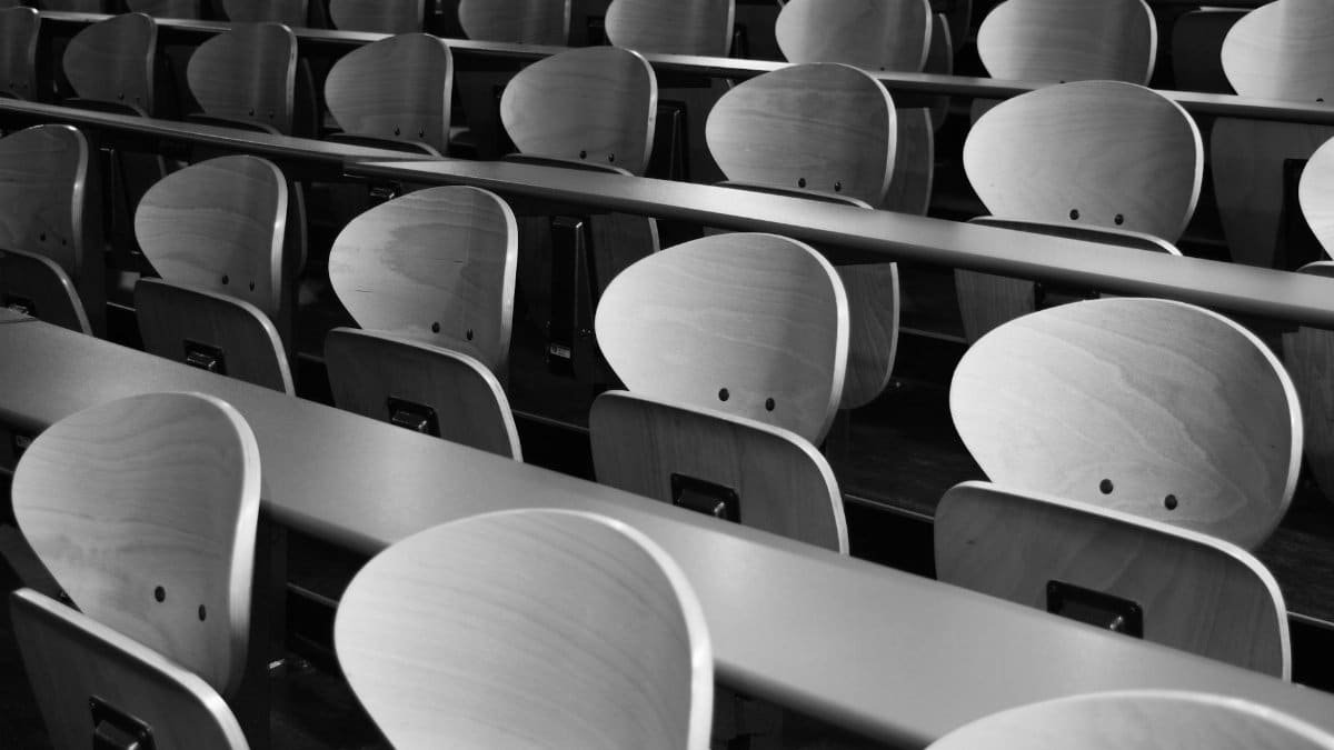 A monochrome view of empty wooden seats in a spacious lecture hall displaying symmetry and design.