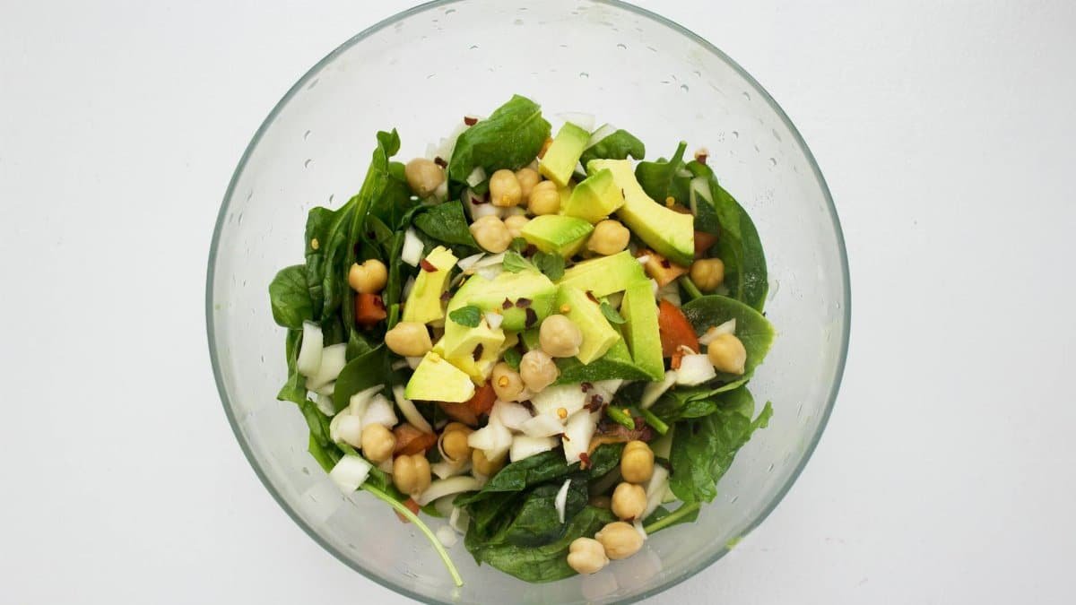 Fresh spinach salad featuring avocado and chickpeas, perfect for healthy eating.