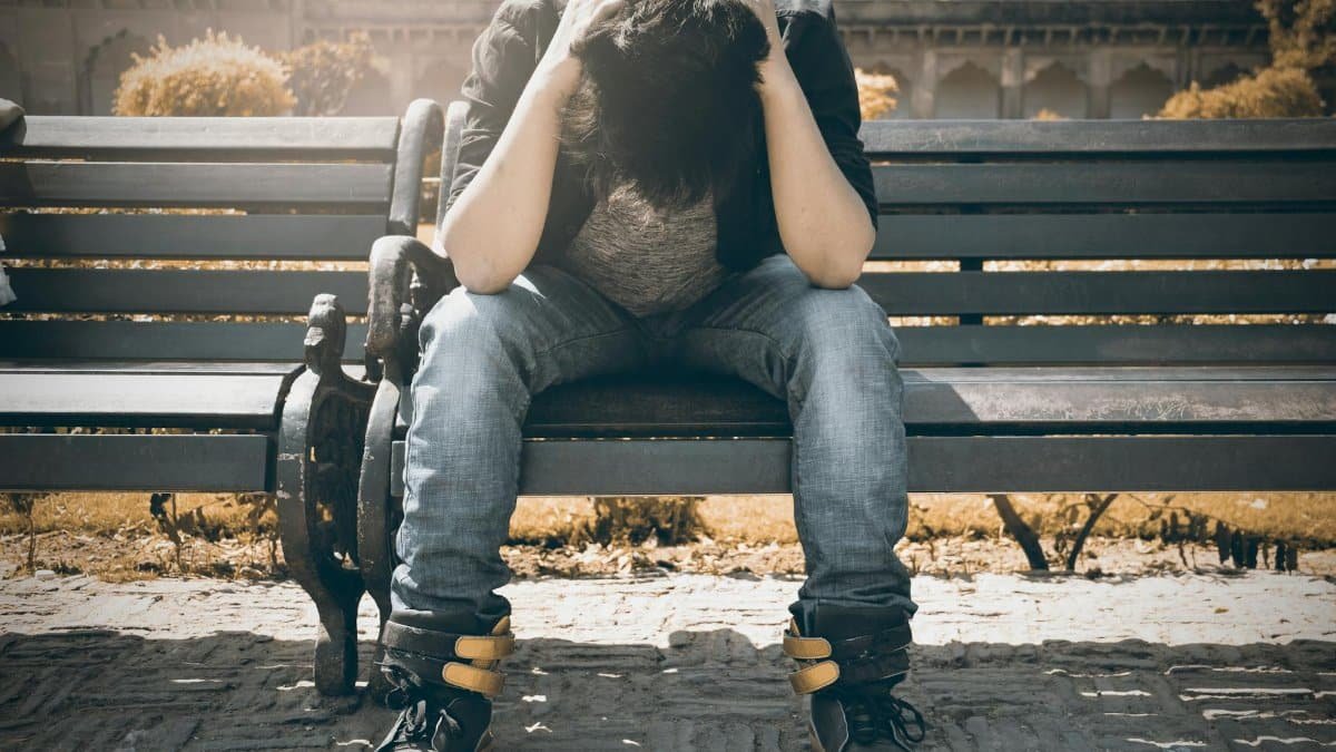Man sitting alone on a bench in Agra, displaying signs of stress and loneliness.