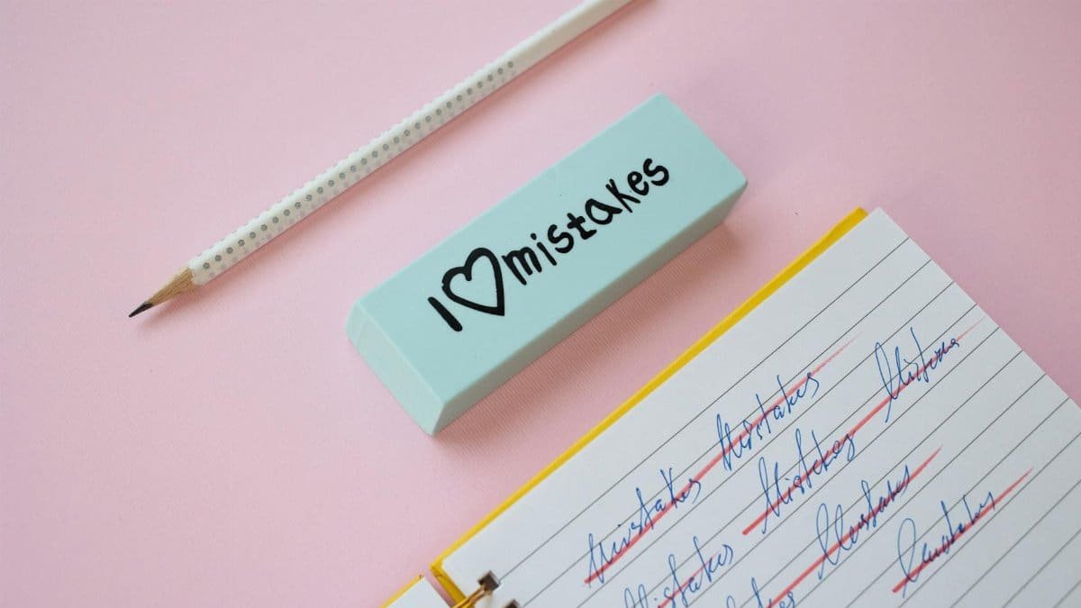 A blue eraser with 'I Love Mistakes' next to a pencil and crossed-out text on a pink background.