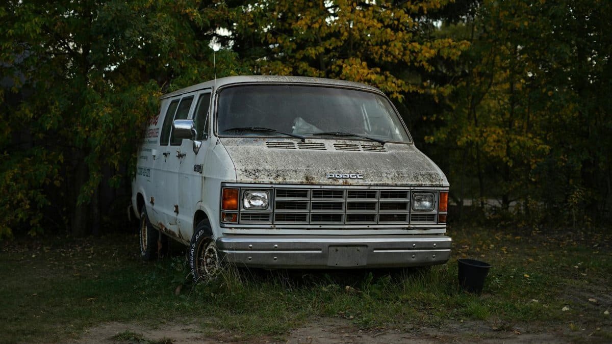 Old Dodge van parked in a forest with autumn leaves in Alberta, Canada.
