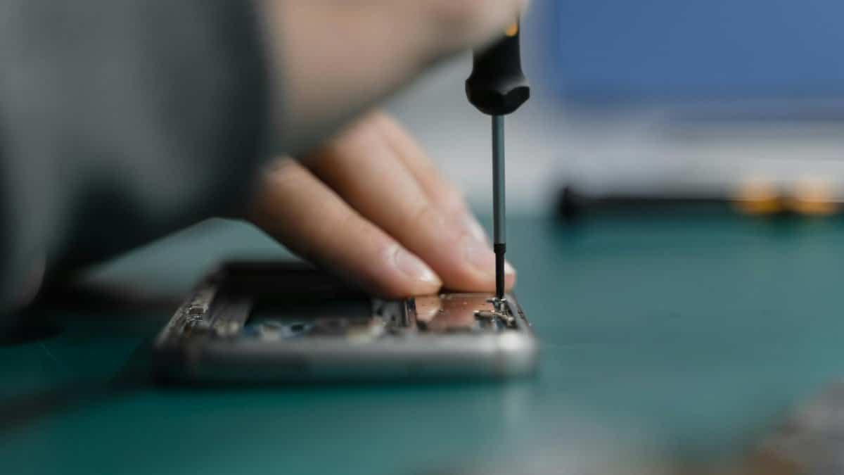 Detailed shot of smartphone repair with a screwdriver and hand close-up.