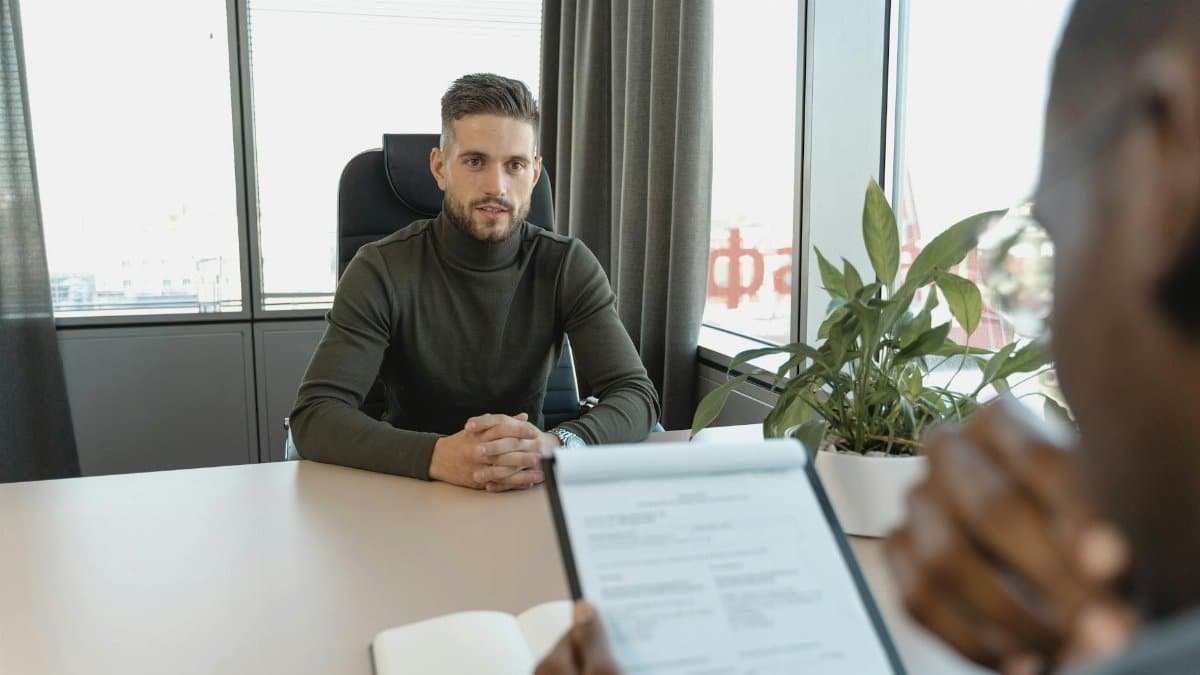 Professional man in turtleneck at office desk during an interview.