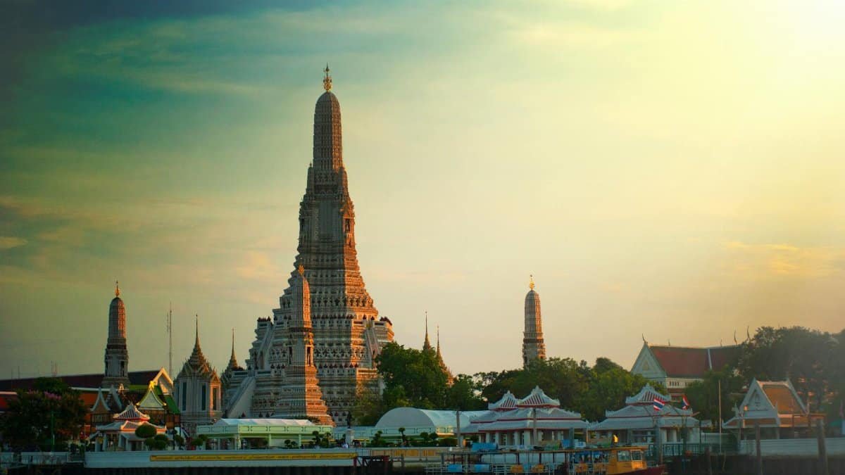 Stunning sunset view of Wat Arun temple by the Chao Phraya River in Bangkok, Thailand.