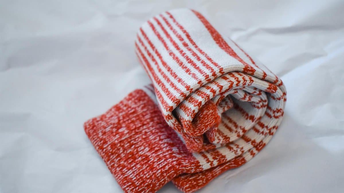 Rolled red and white striped winter socks on a minimal white surface, perfect for comfort and warmth.