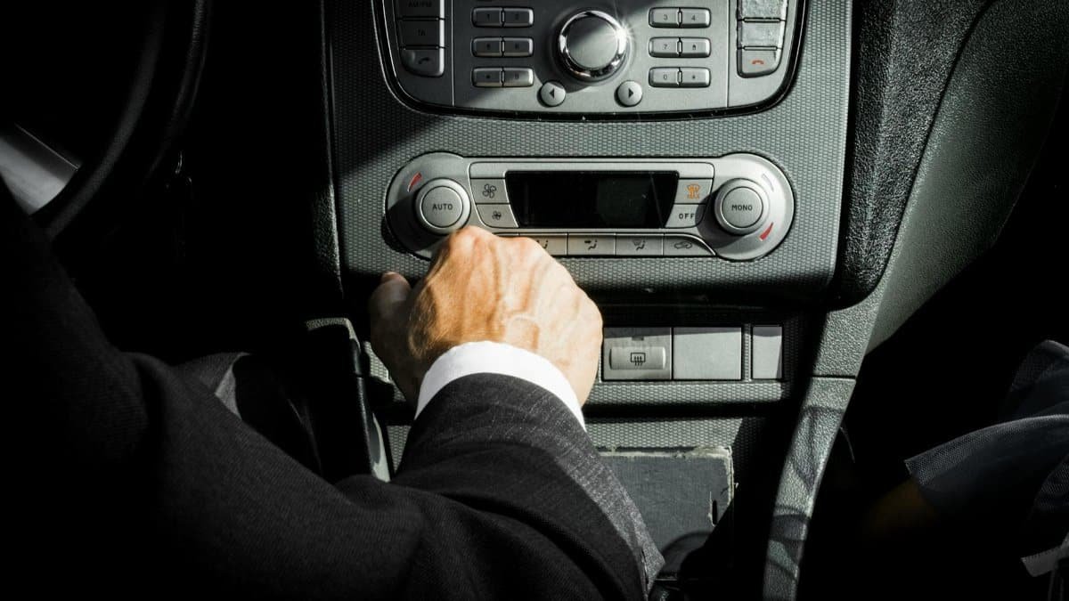 Close-up of a driver in a suit operating the car dashboard controls, capturing a professional interior setting.