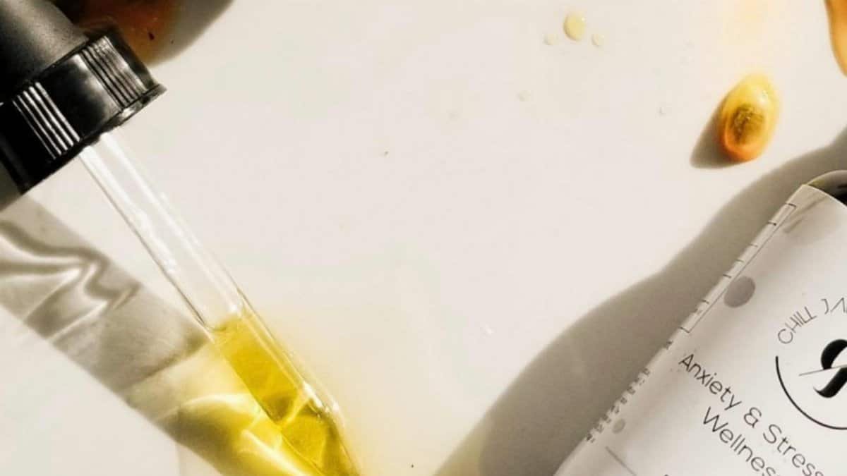 Overhead view of wellness oil dropper with spilled passionfruit seeds on surface, depicting a natural, holistic lifestyle.