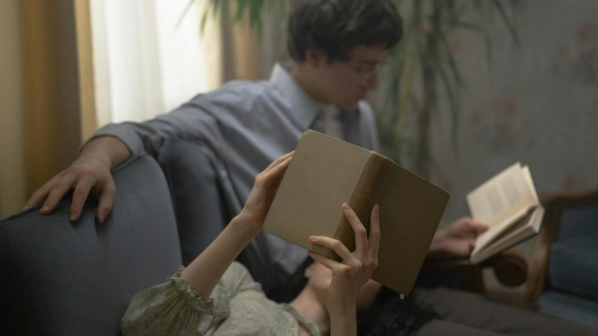 A couple enjoys a quiet reading session together on a comfortable sofa indoors.