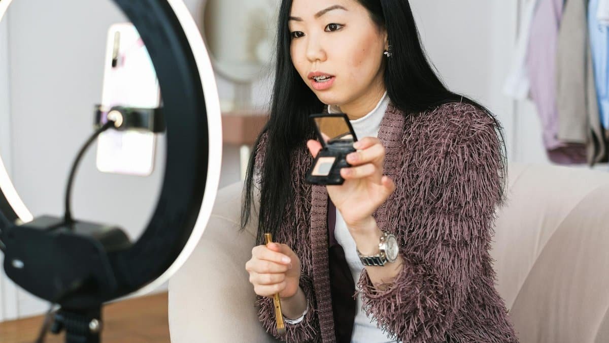 Young woman recording a makeup tutorial with a ring light for her vlog.