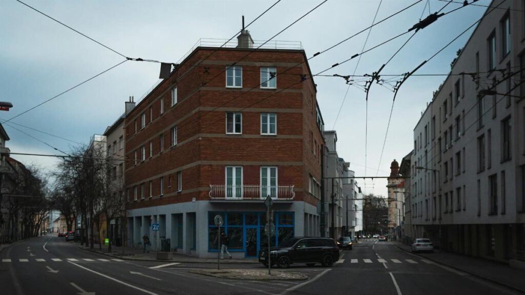 A red brick building at a quiet urban street intersection with overhead cables.