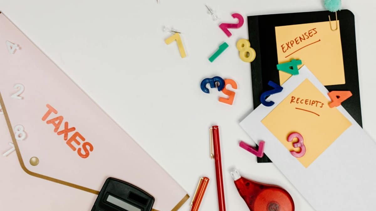 Flat lay of tax documents, receipts, calculator, and colorful numbers for budgeting.