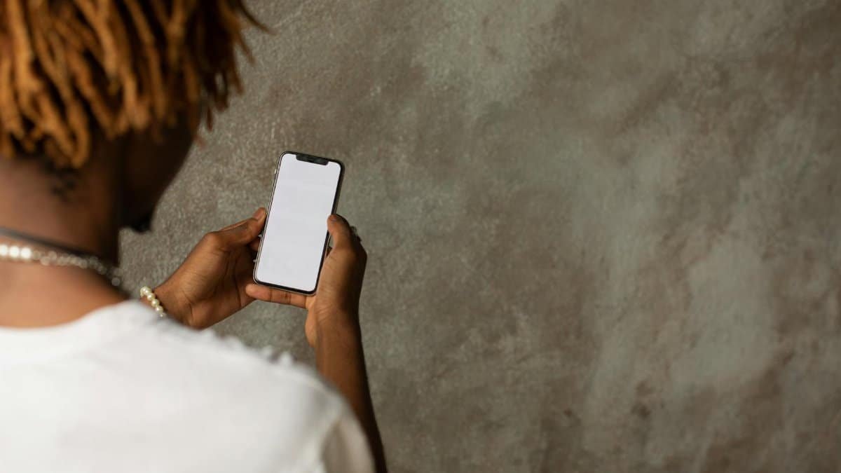 A young adult holding a smartphone with a blank screen, suitable for mockup use.