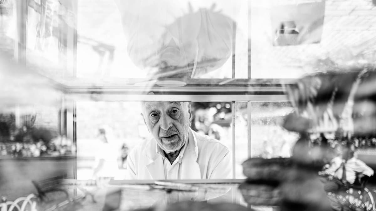Captivating black and white portrait of a vendor in Istanbul, Turkey, behind a display case.