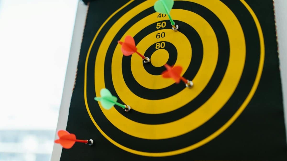 Vibrant darts stuck in a yellow and black dartboard representing precision and strategy.