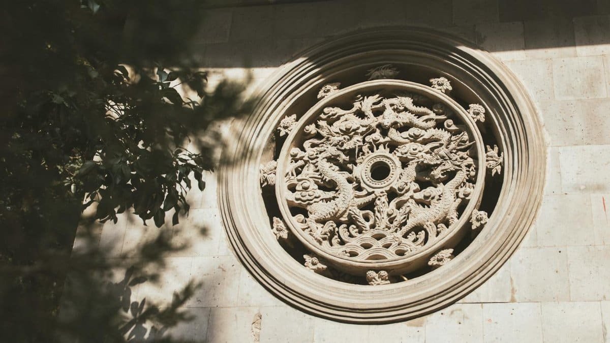 Close-up of an ornate round stone carving featuring dragons on an exterior wall.