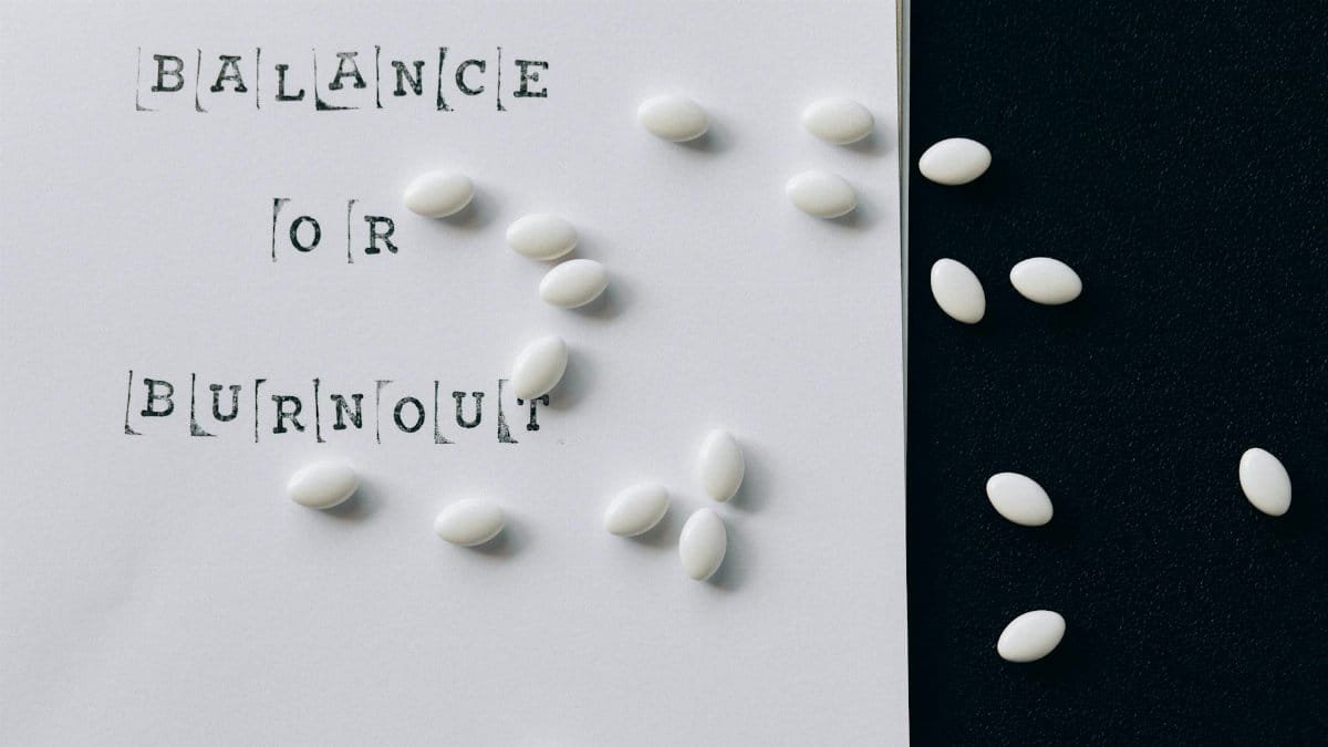 Conceptual image featuring 'Balance or Burnout' text with scattered white capsules.