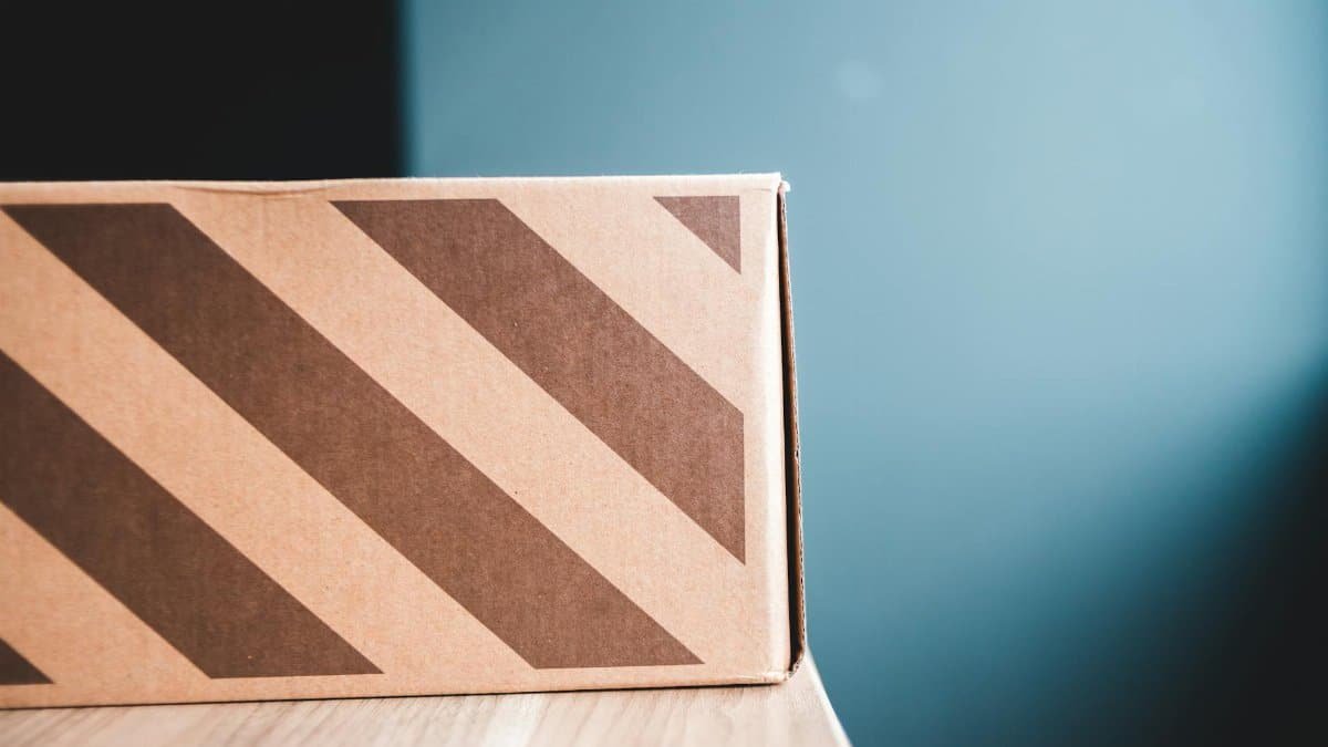Closeup of carton box with stripes on wooden table against gray wall in apartment