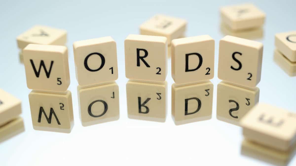 Scrabble tiles spelling 'words' on glass reflecting surface, perfect for language and games themes.