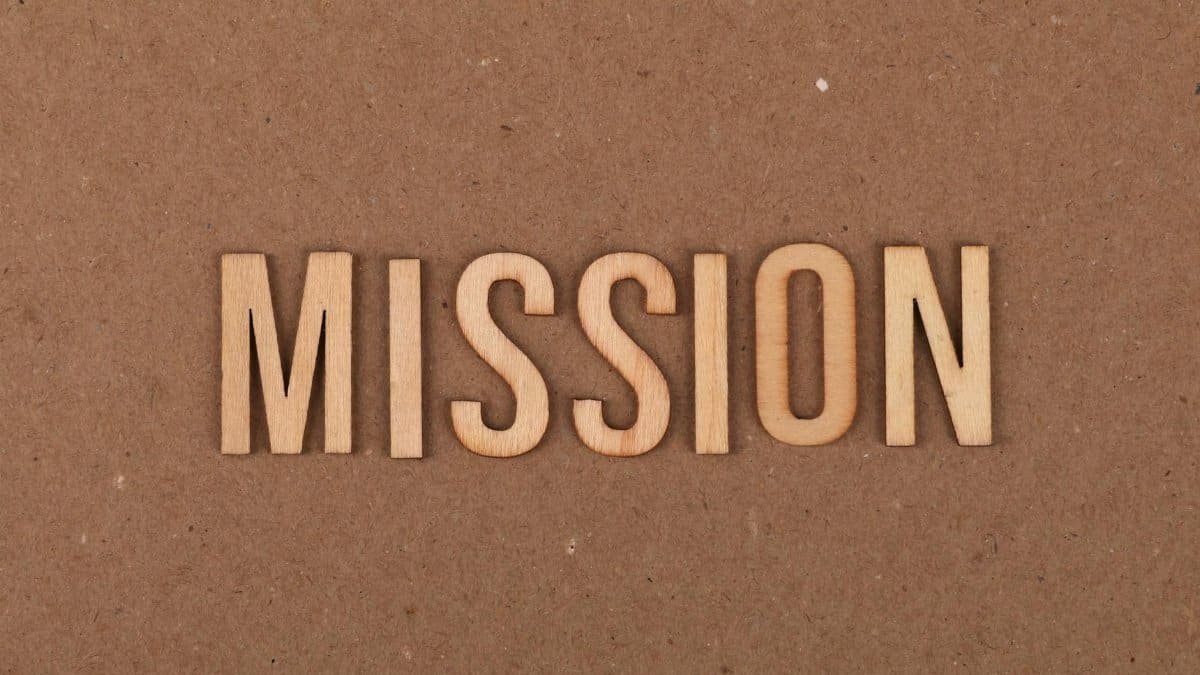 Wooden letters spelling 'MISSION' on textured cardboard background, emphasizing goals and purpose.