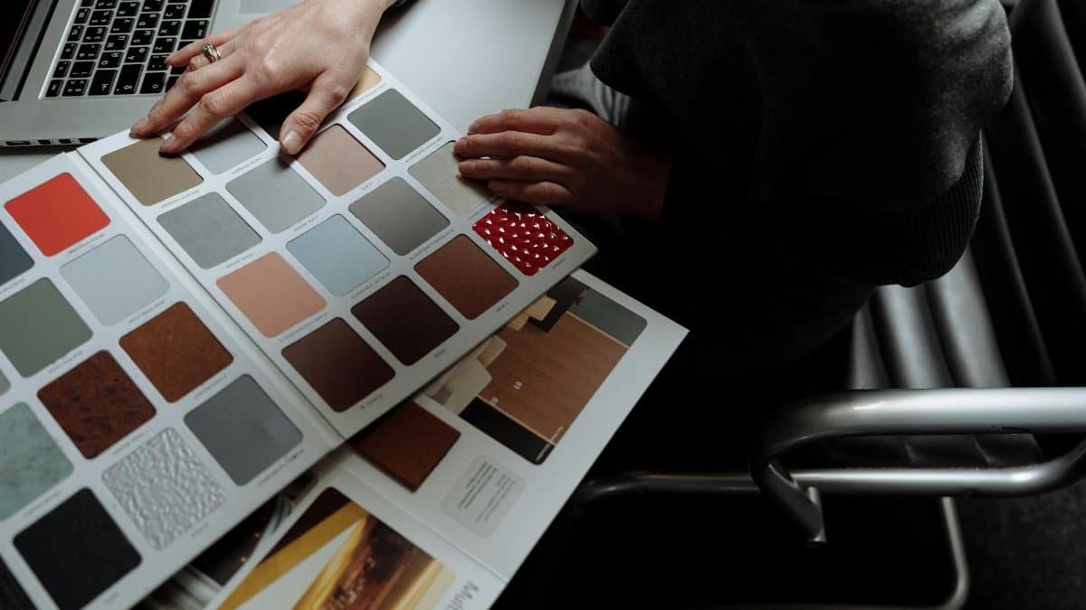 Interior designer on laptop reviewing color swatches for design project. Overhead view, modern workspace.