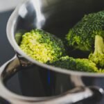 Close-up of fresh broccoli being cooked in a stainless steel pot, showcasing healthy eating.