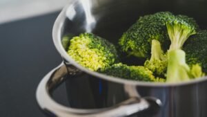 Close-up of fresh broccoli being cooked in a stainless steel pot, showcasing healthy eating.