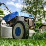 Close-up view of a lawn mower cutting grass in a garden on a sunny day.