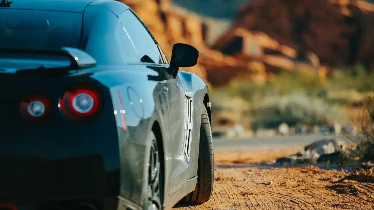 A black car parked in the scenic Nevada desert, showcasing its sleek back view.
