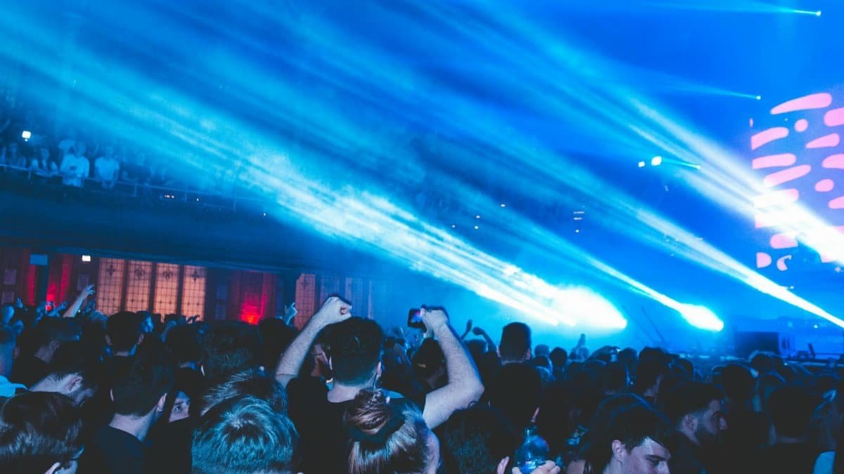 Vibrant nightclub scene with crowd enjoying music and blue laser lights.