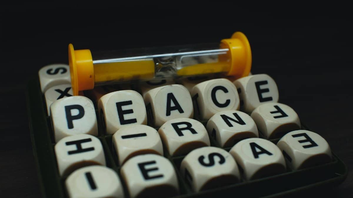 A creative arrangement of dice spelling 'PEACE' with an hourglass, symbolizing time and tranquility.