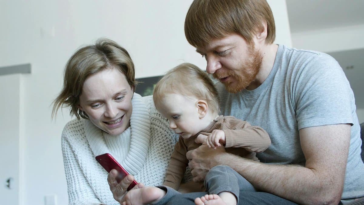 A family enjoying quality time together at home, interacting with a smartphone.