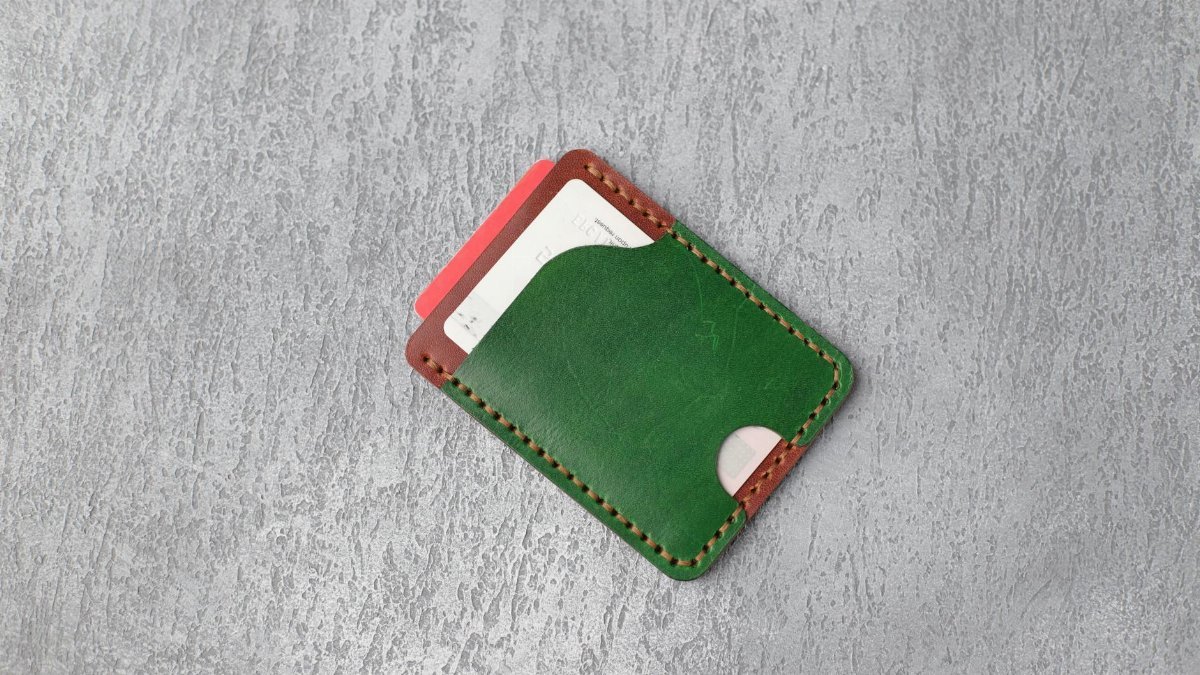Stylish green leather wallet on textured gray surface showcasing minimalistic design.