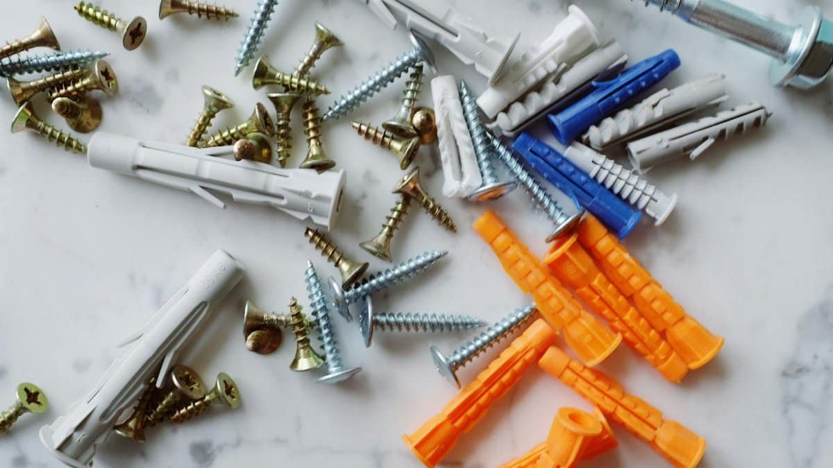 A detailed arrangement of screws and wall anchors on a marble surface, ideal for DIY projects.