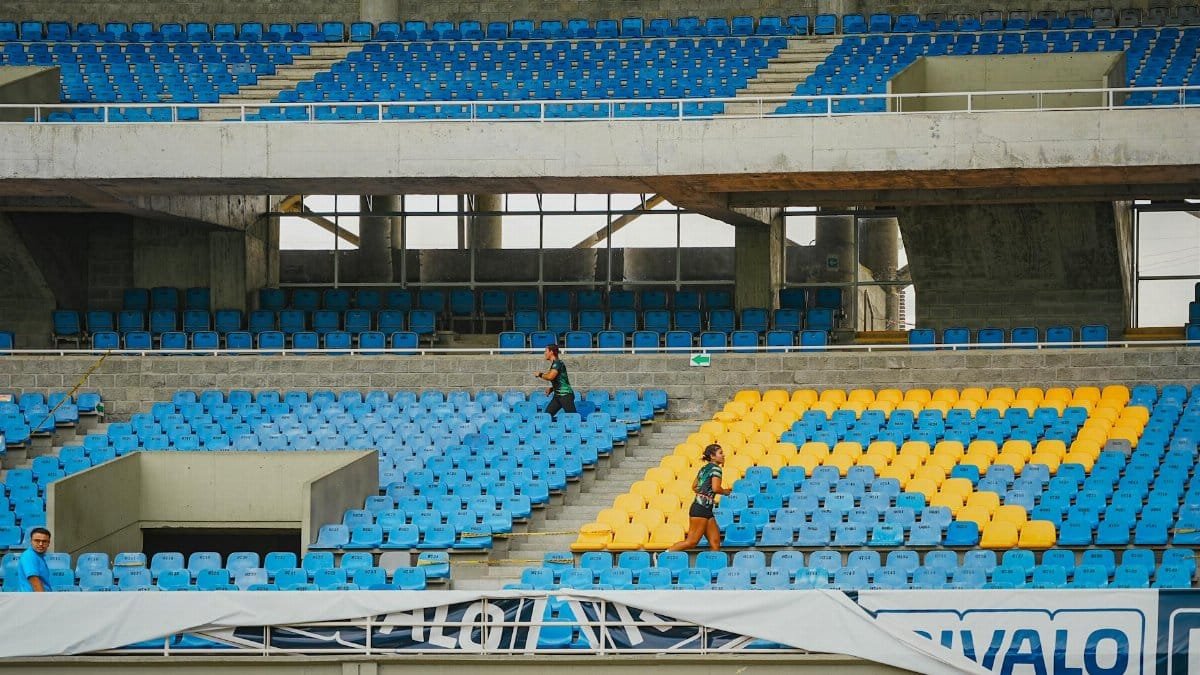 Athletes running up stadium stairs for endurance training on bright seats.