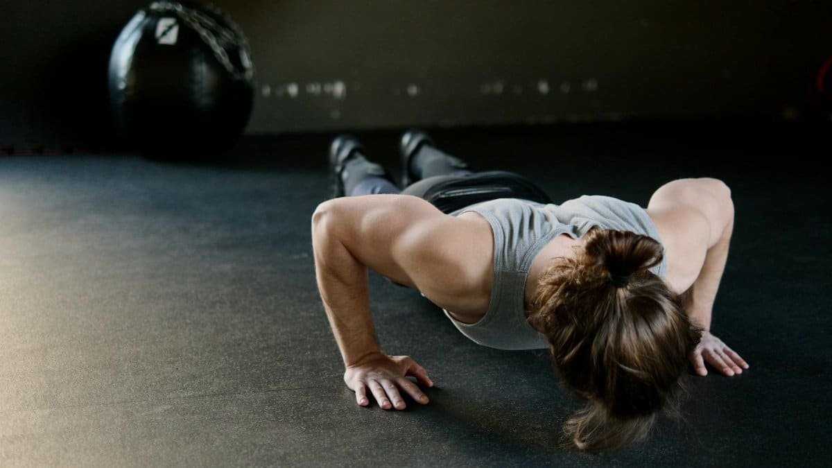 Strong male engaged in push-up exercise on gym floor, showcasing upper body strength.