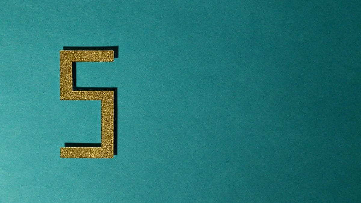 Abstract photo featuring a golden number five on a teal background with negative space.