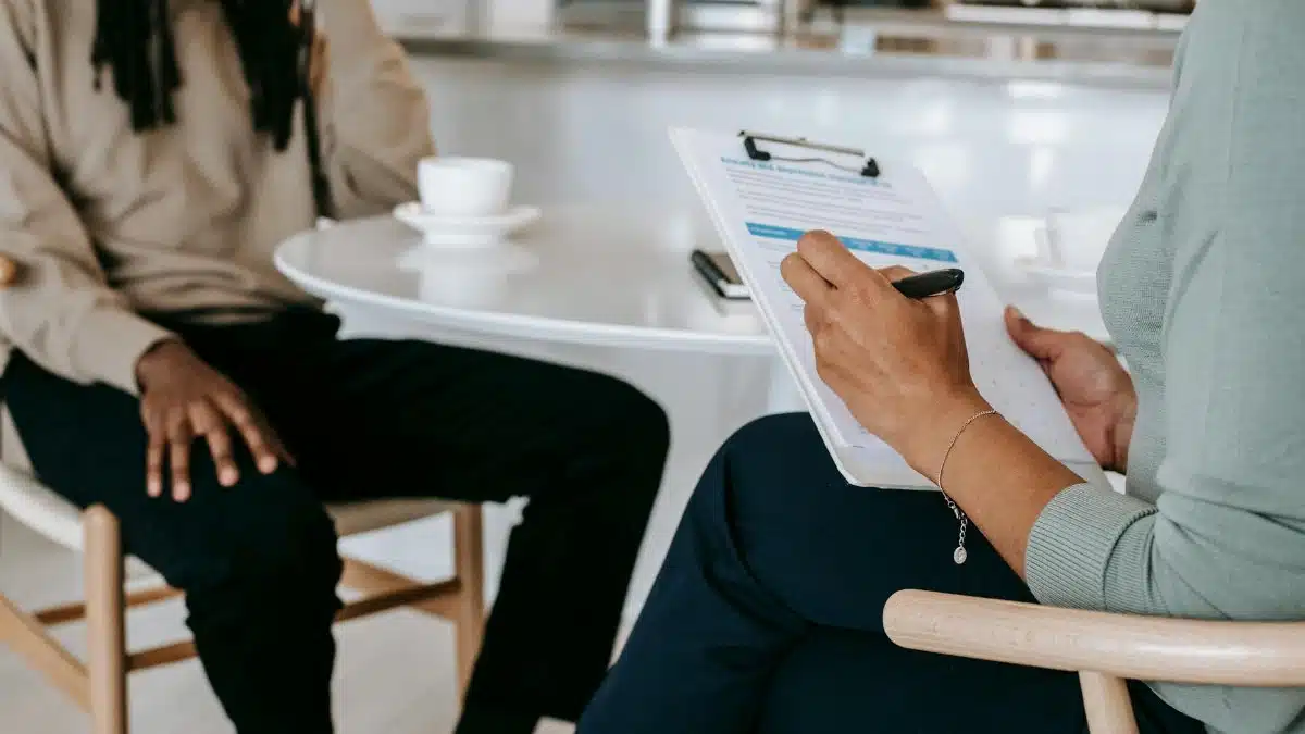 Two professionals engaged in a consultation, one taking notes on a clipboard.