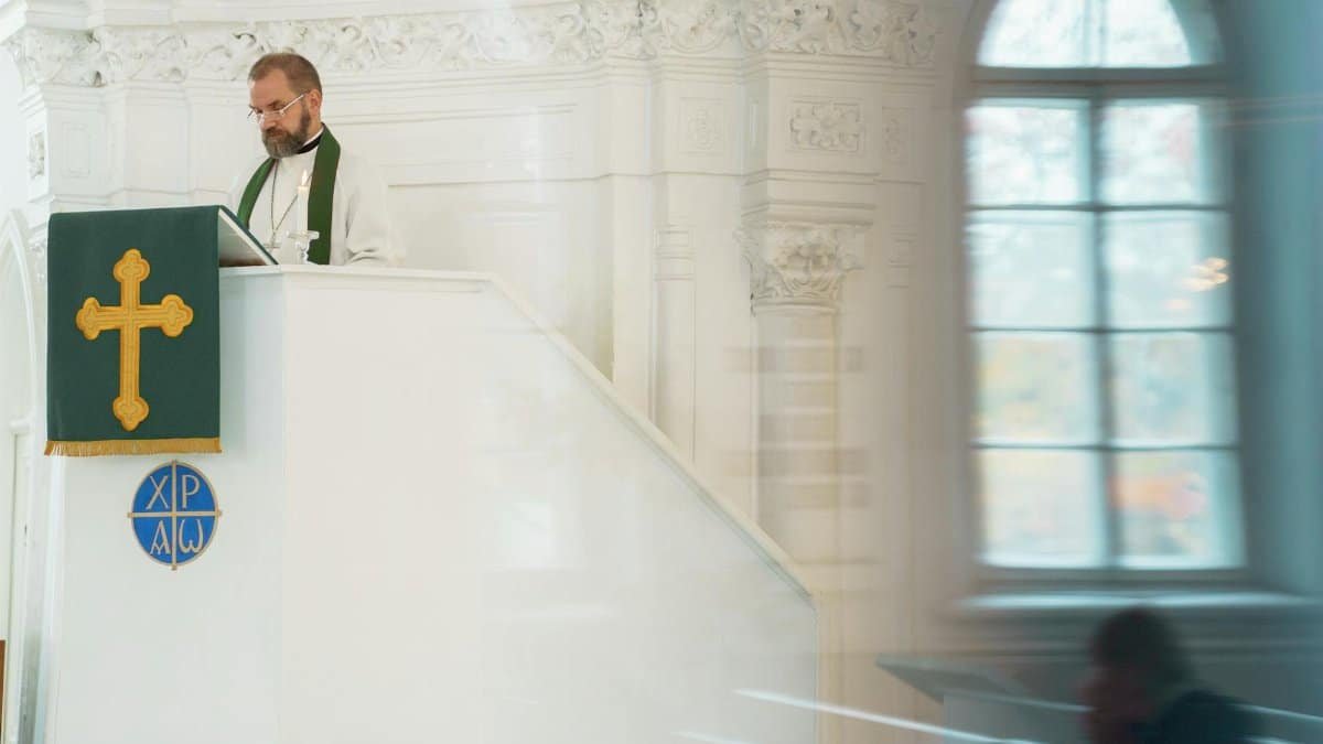 A preacher standing at a pulpit inside a historic church during a religious ceremony.