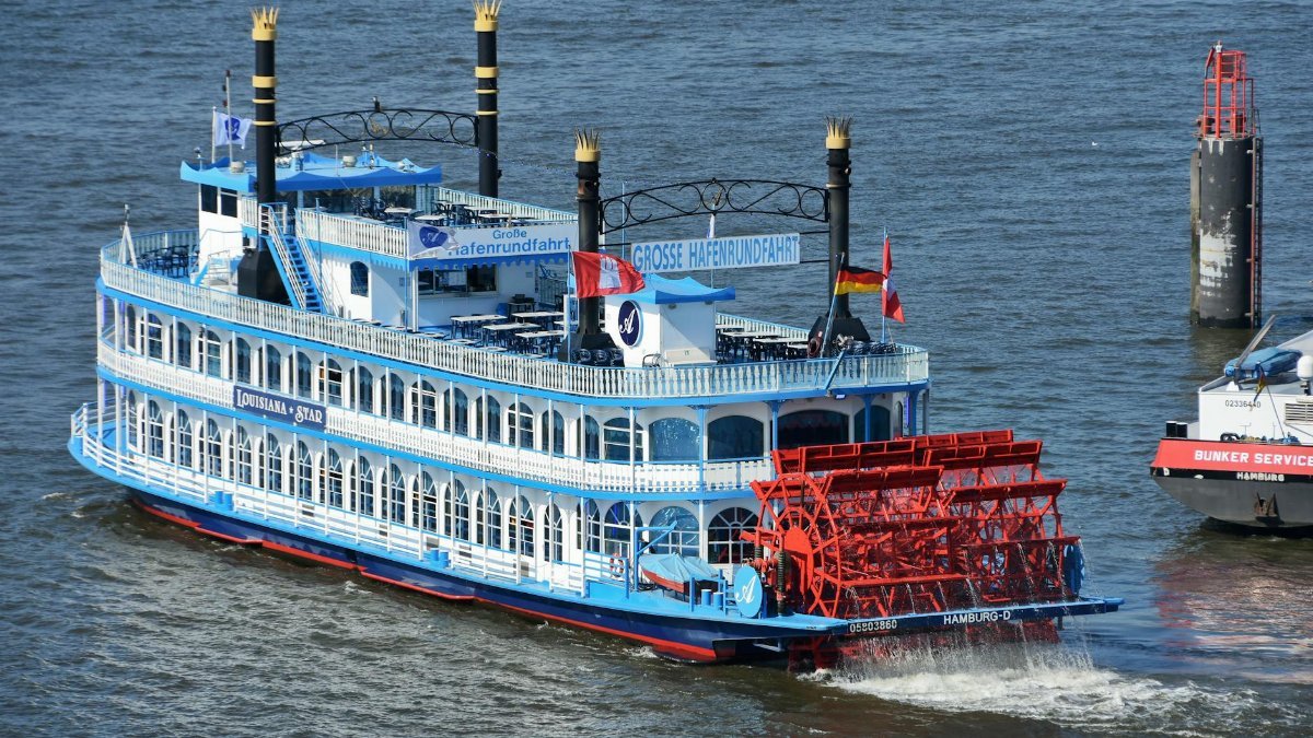 Paddle steamer Louisiana Star navigating through Hamburg's bustling port waters.