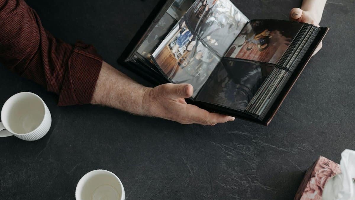 Hands holding a photo album with coffee cups, evoking memories and nostalgia.