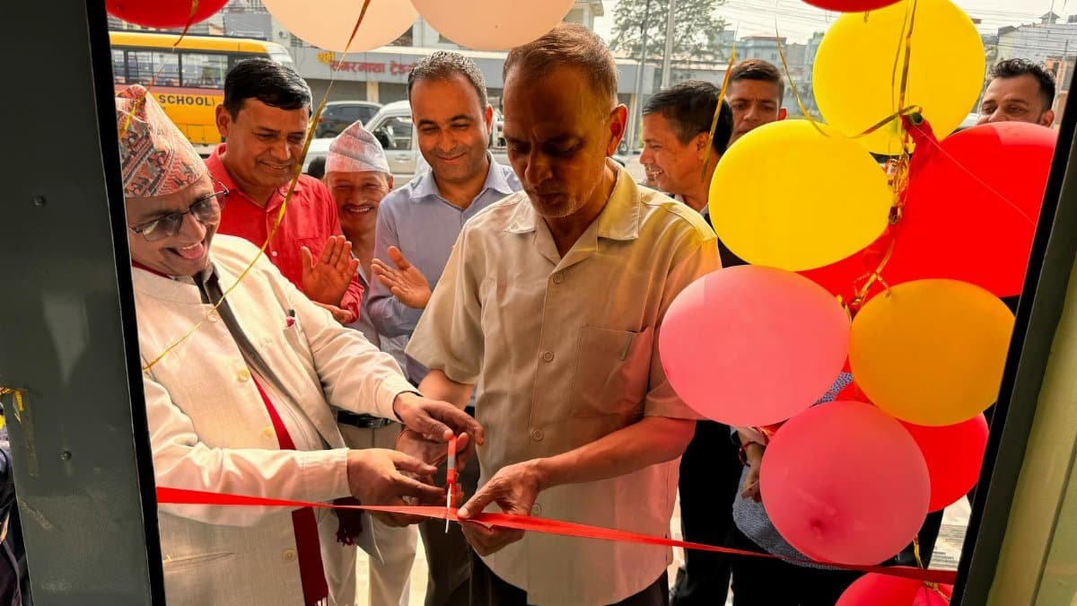 A group of men cutting a ribbon for an opening ceremony decorated with balloons.