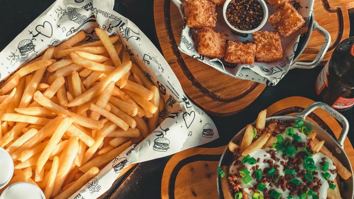 Delicious platter of crispy fries, loaded fries, cheese bites, and dips on a rustic wooden table.
