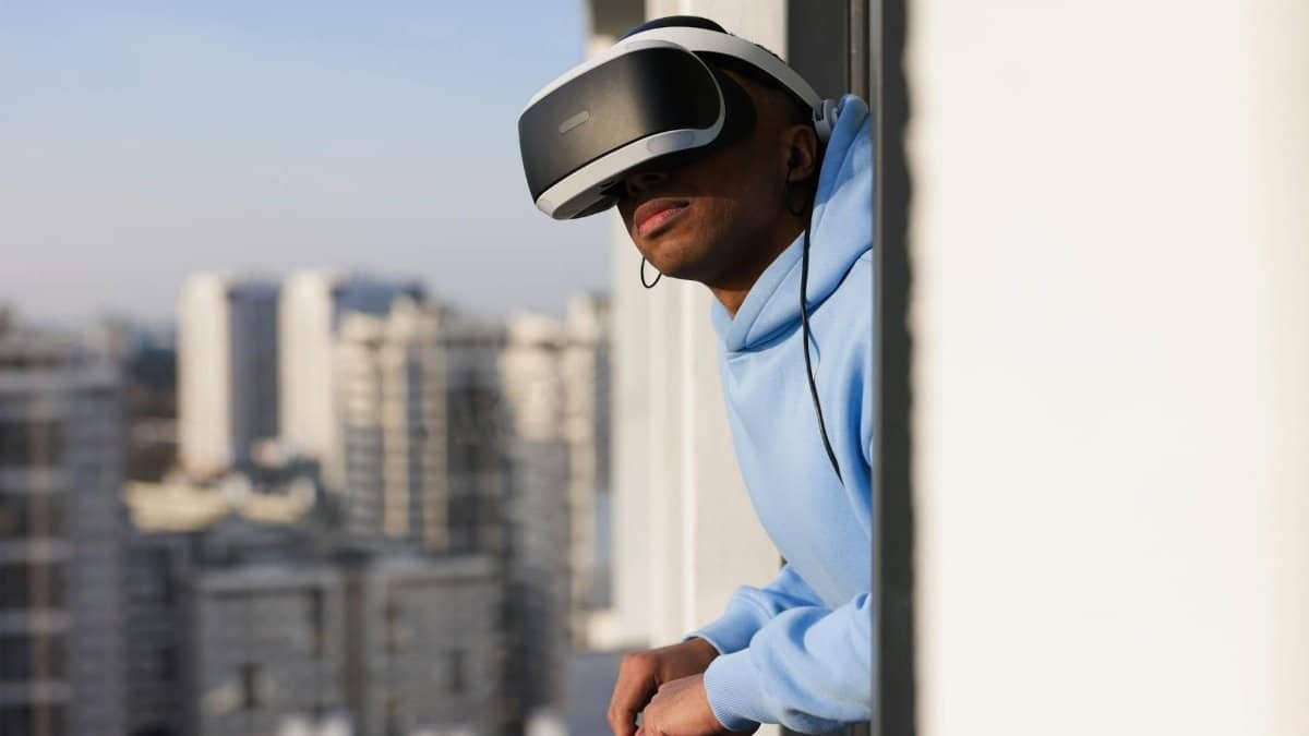 Young man experiencing virtual reality outdoors on a balcony with a VR headset.